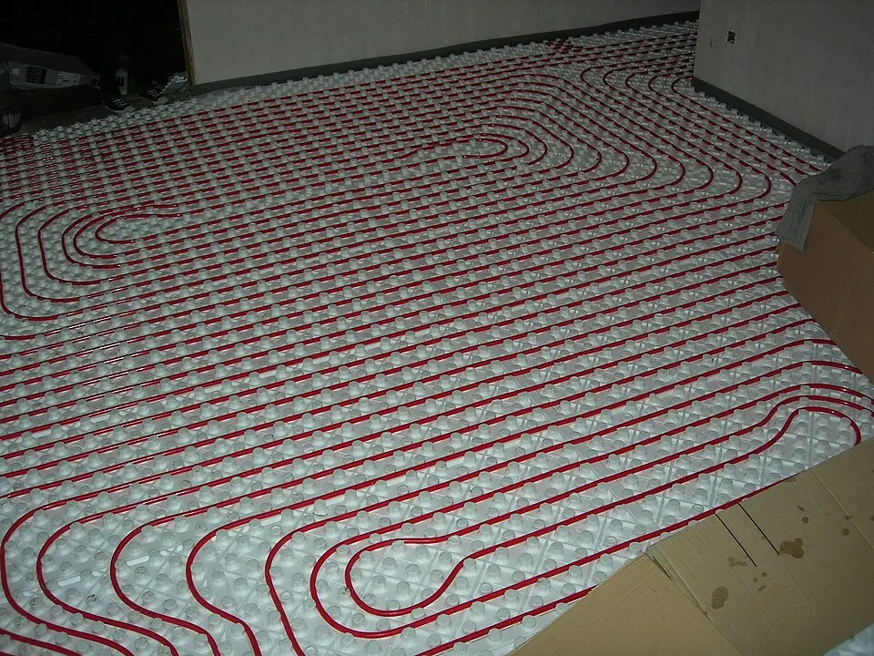 Boucles de chauffage au sol posées sur des panneaux isolants à plots.
