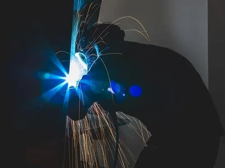 Soudure d'une conduite au poste à souder : arc et gerbe d'étincelles.