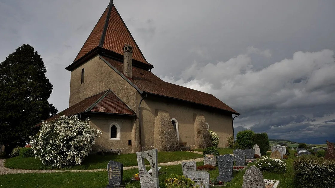 L'église Notre-Dame de Bassins et son cimetière, sous un ciel d'orage