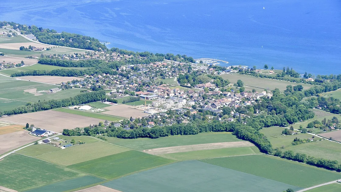 Vue aérienne du village de Crans (VD), champs et lac au second plan