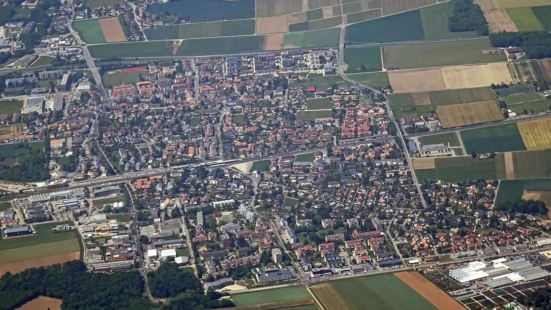 Vue aérienne de Gland, ses quartiers et ses zones d'activité entre le lac et les champs