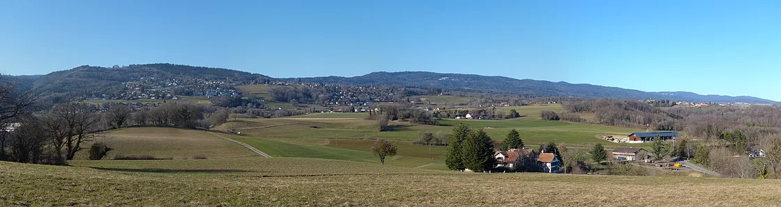 Vue depuis le Bochet sur les pres et les toits d'Arzier-Le Muids, le Jura a l'arriere-plan
